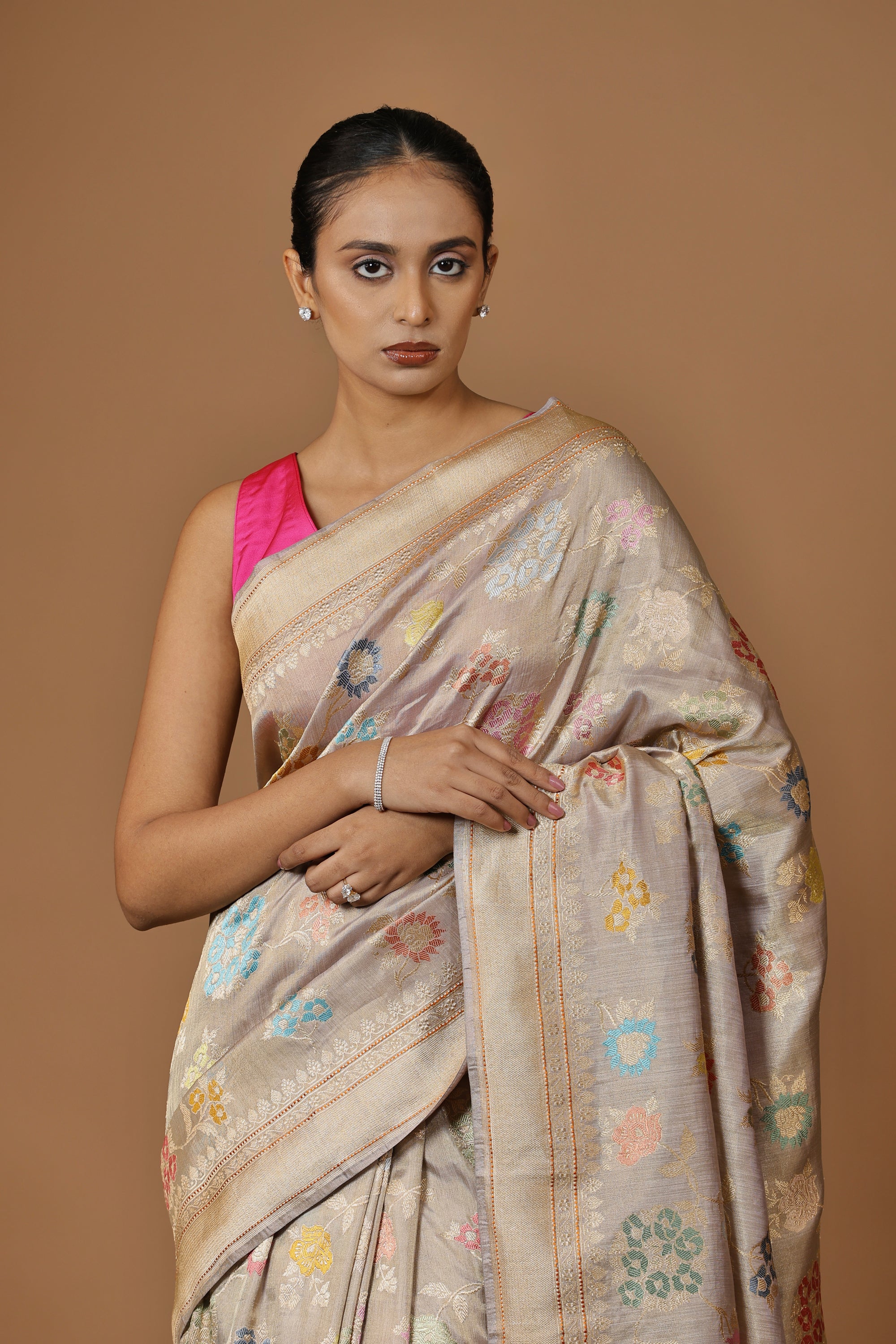 Handwoven Banarasi tissue silk sari in soft silver, featuring vibrant meenakari floral motifs and a golden border.