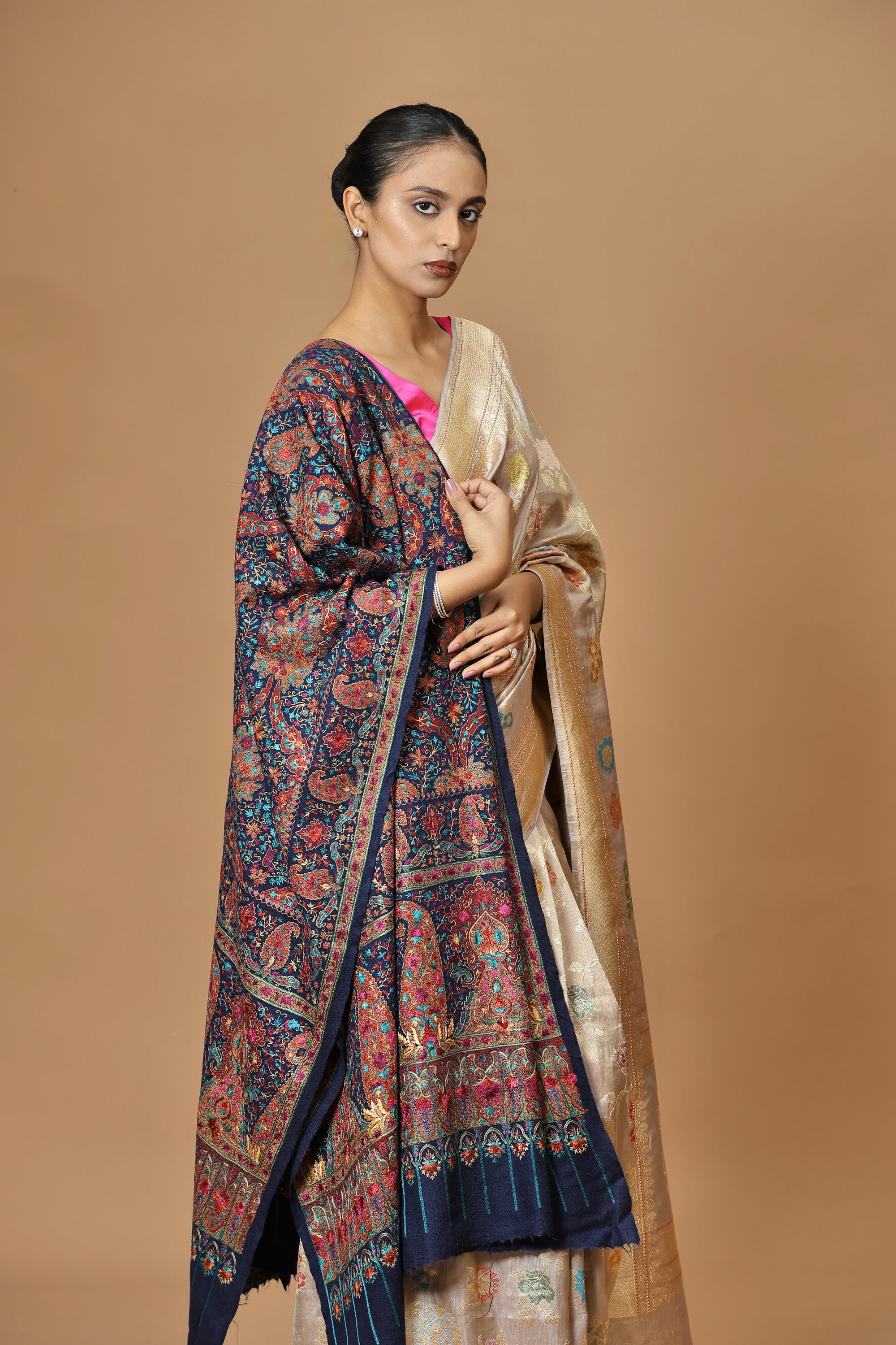 Handwoven Banarasi tissue silk sari in soft silver, featuring vibrant meenakari floral motifs and a golden border.