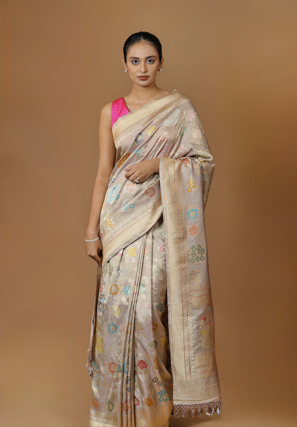 Handwoven Banarasi tissue silk sari in soft silver, featuring vibrant meenakari floral motifs and a golden border.
