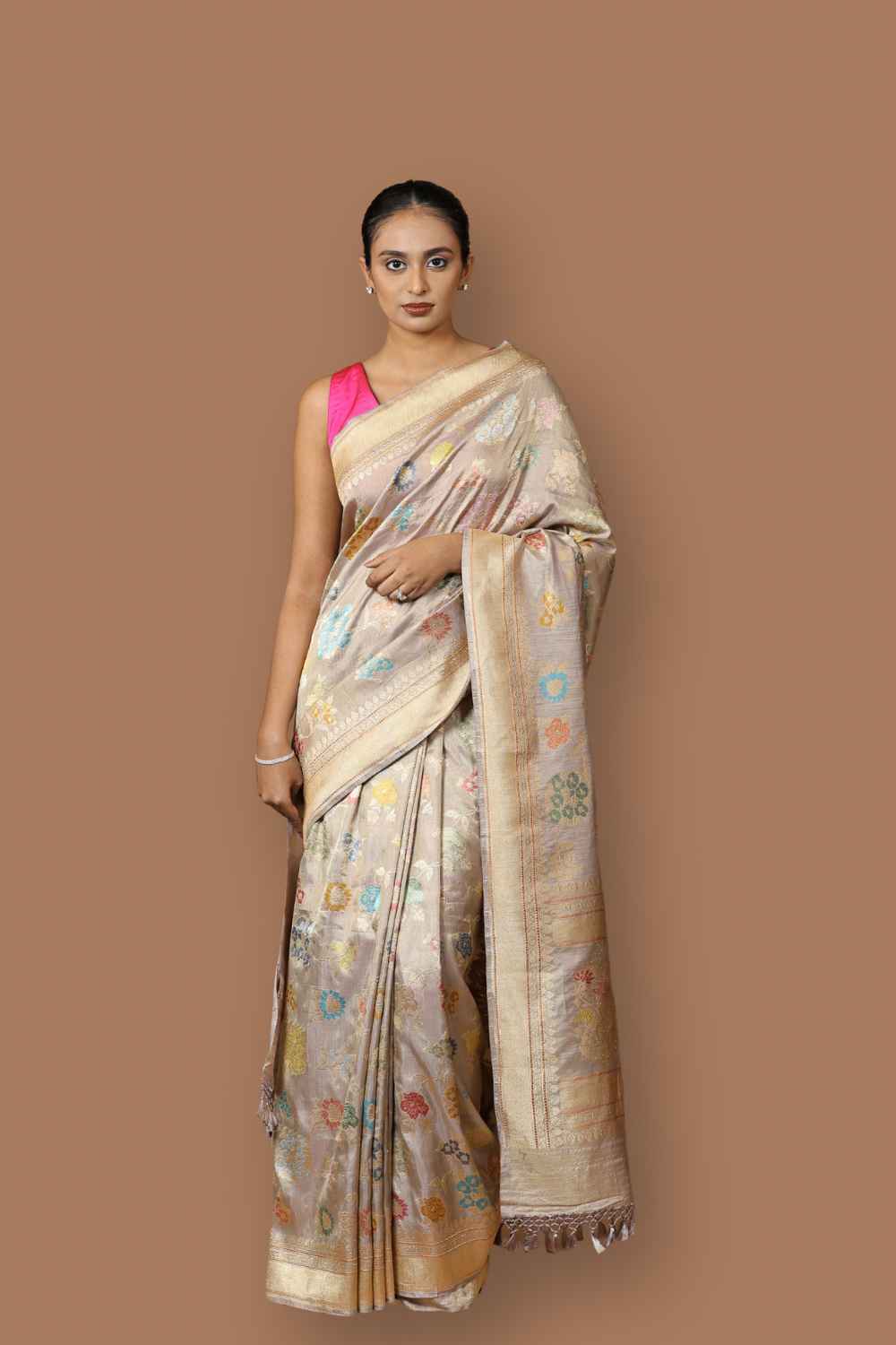 Handwoven Banarasi tissue silk sari in soft silver, featuring vibrant meenakari floral motifs and a golden border.