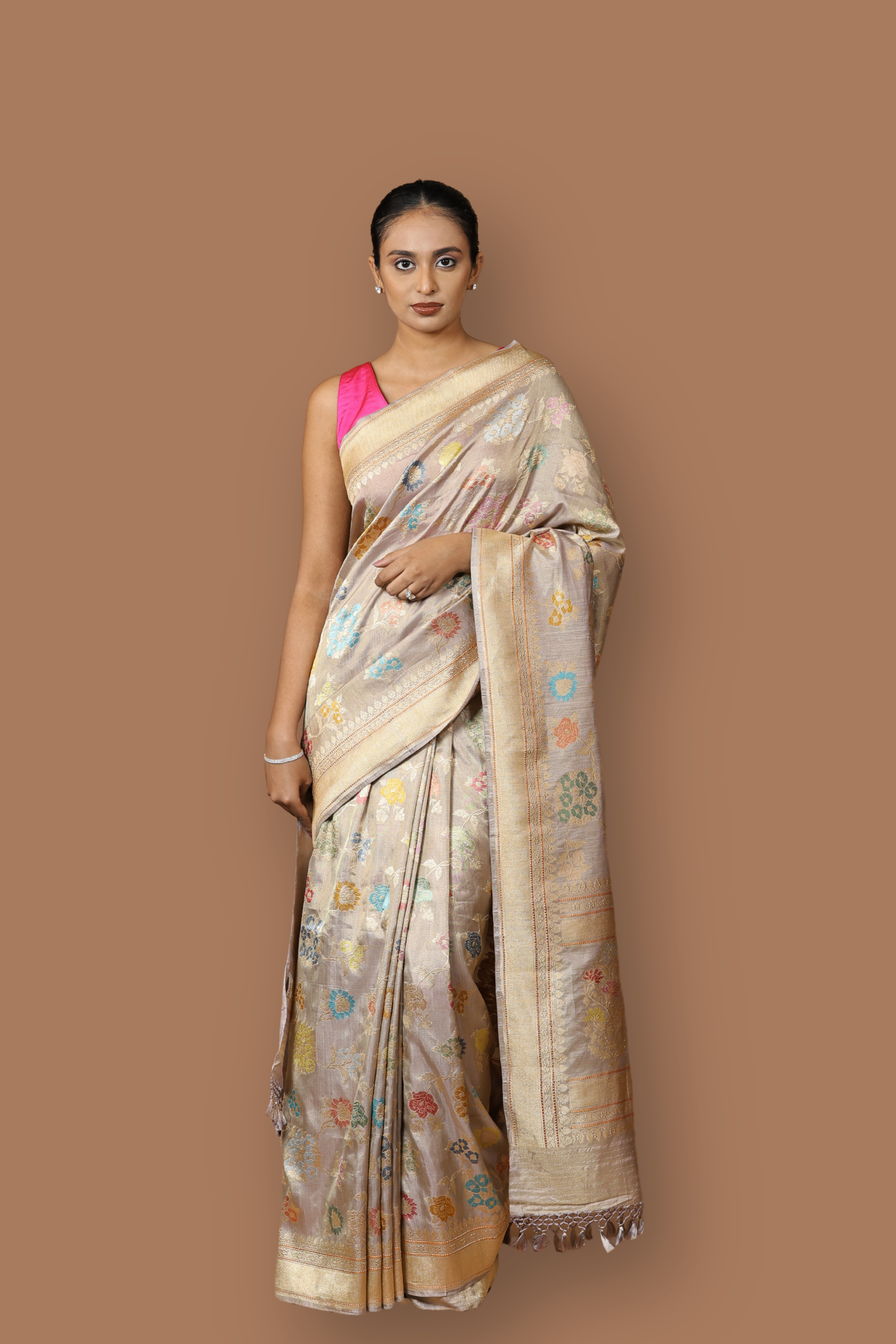 Handwoven Banarasi tissue silk sari in soft silver, featuring vibrant meenakari floral motifs and a golden border.